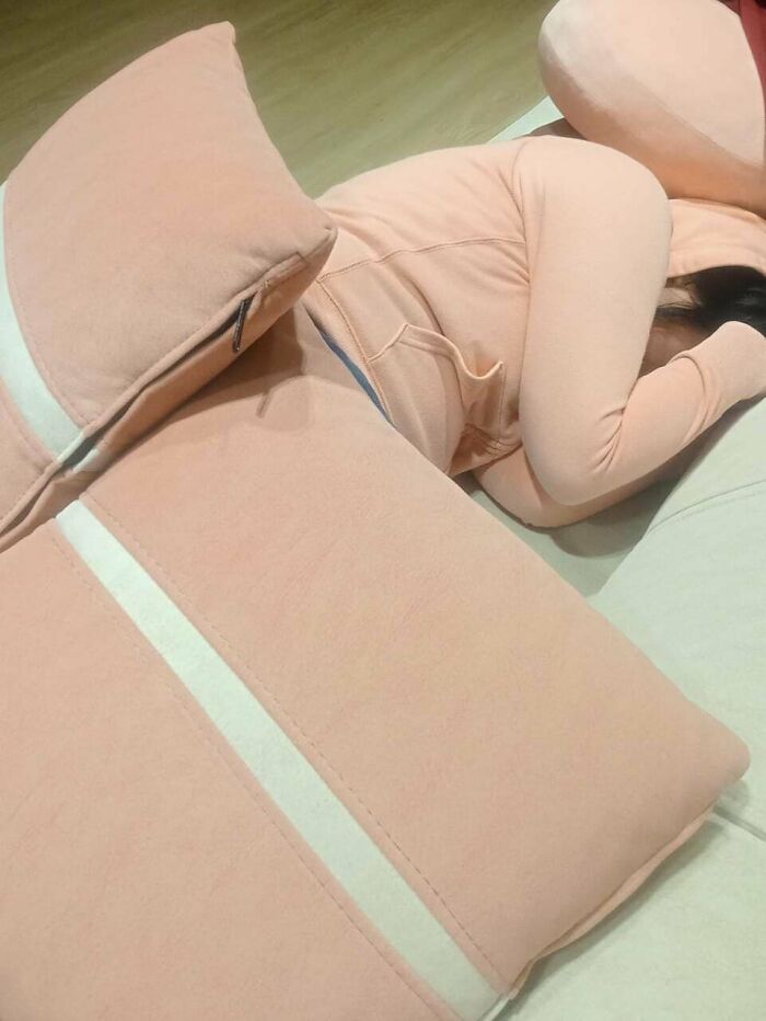 A person in a pink hoodie lies on a pink cushion, an accidental color match creating a satisfying photo to lower cortisol levels.