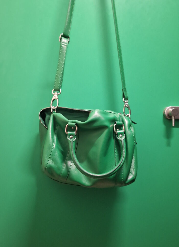 A vibrant green leather handbag perfectly matches the green wall it hangs on, an accidental color match that may lower cortisol levels.