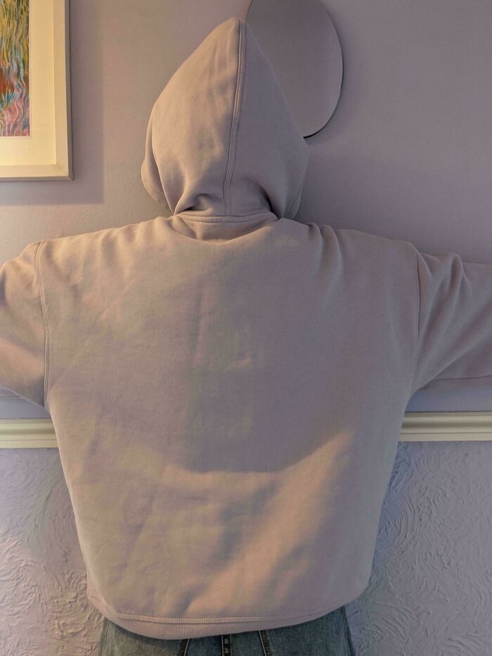 A person in a light purple hoodie facing a lavender wall, an accidental color match that may lower cortisol levels.