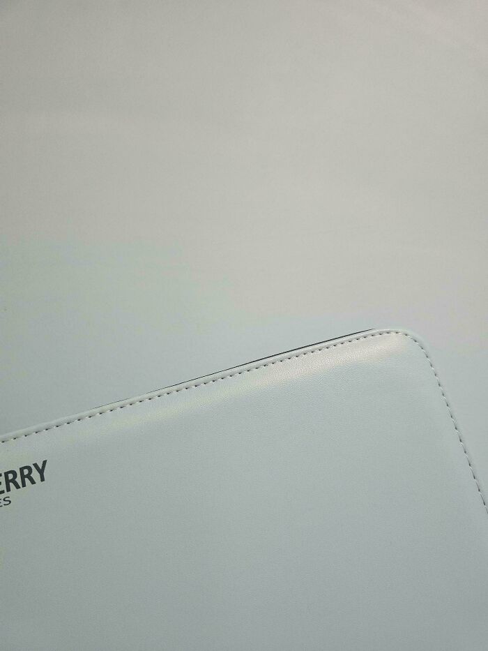 A closeup of a light blue leather bag, revealing the stitching details and part of the word "ERRY", an accidental color match.