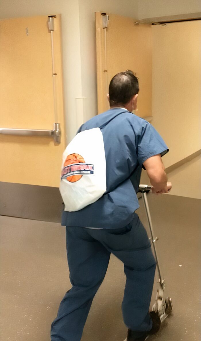 A doctor in scrubs and a basketball bag rides a scooter down a hospital hall, showcasing doctors awesome sense of humor.
