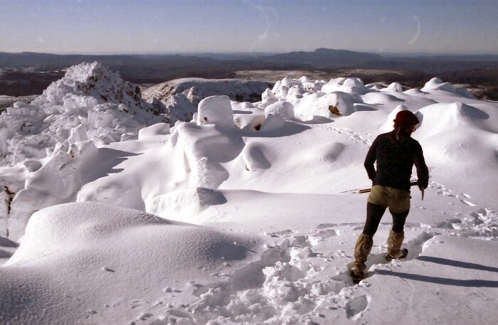 Snow-covered mountain landscape with a person hiking through pristine snow