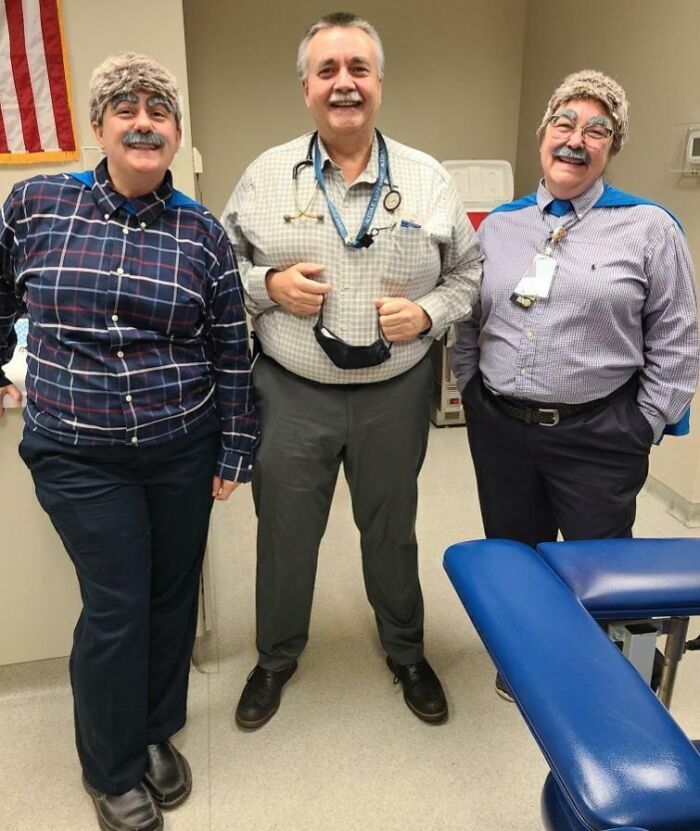 Doctors showing awesome sense of humor, two wearing wigs and mustaches, one smiling at the camera.