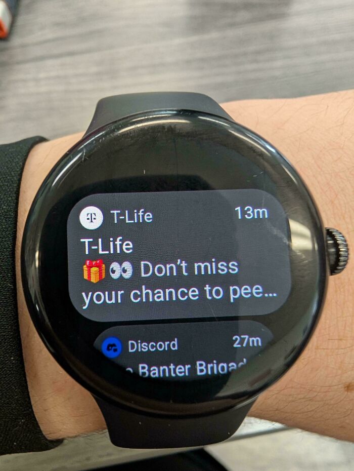 A smartwatch displays a prematurely truncated T-Life notification, creating a funny, unexpected message about missing your chance to pee.