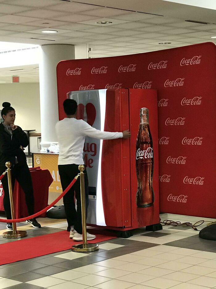 Person interacting with Coca-Cola vending machine at university event