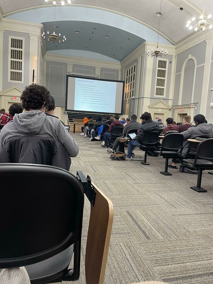 Students attending a lecture in a university classroom with projector screen