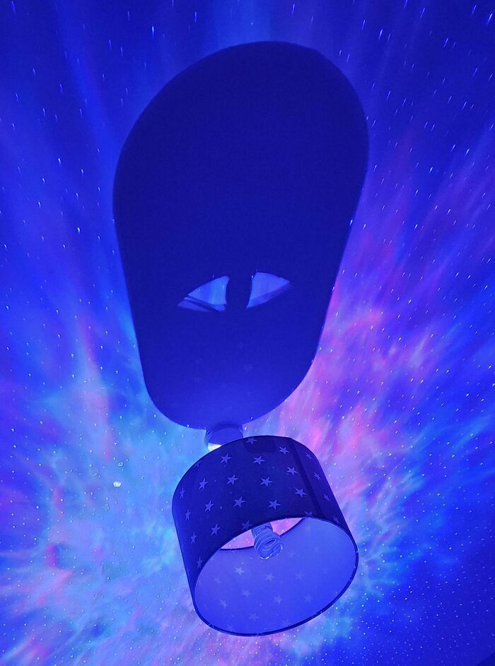 Lamp and shadows project alien face pareidolia with blue starry light
