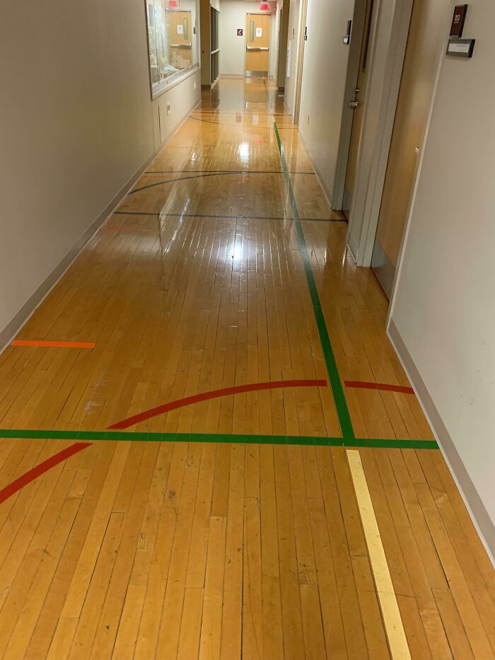 Hallway floor marked with multifunctional colored gym lines in educational building