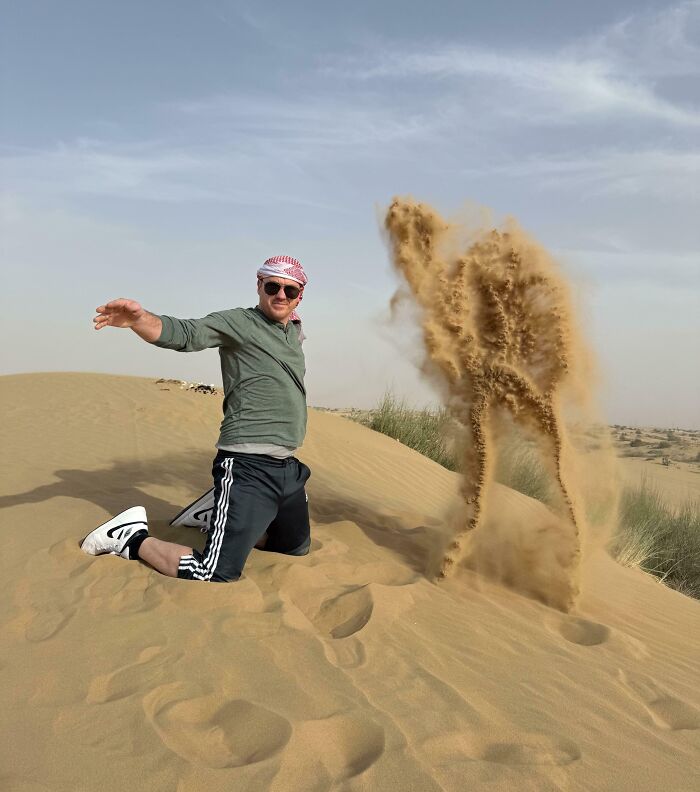 Man in desert throwing sand with sand shaped like a dancing figure in pareidolia