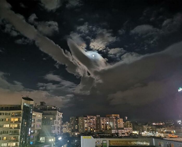 Night cityscape with clouds showing a pareidolia shape near the moon