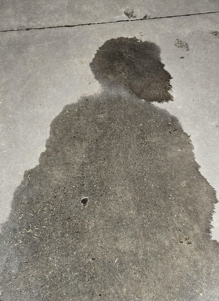 Wet stain on pavement resembling a human silhouette