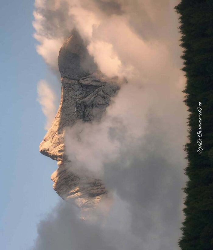 Mountain peak and clouds forming a giant human face pareidolia silhouette