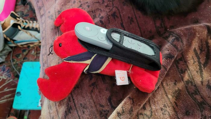 A creative handmade project featuring a plush lobster holding a remote control.