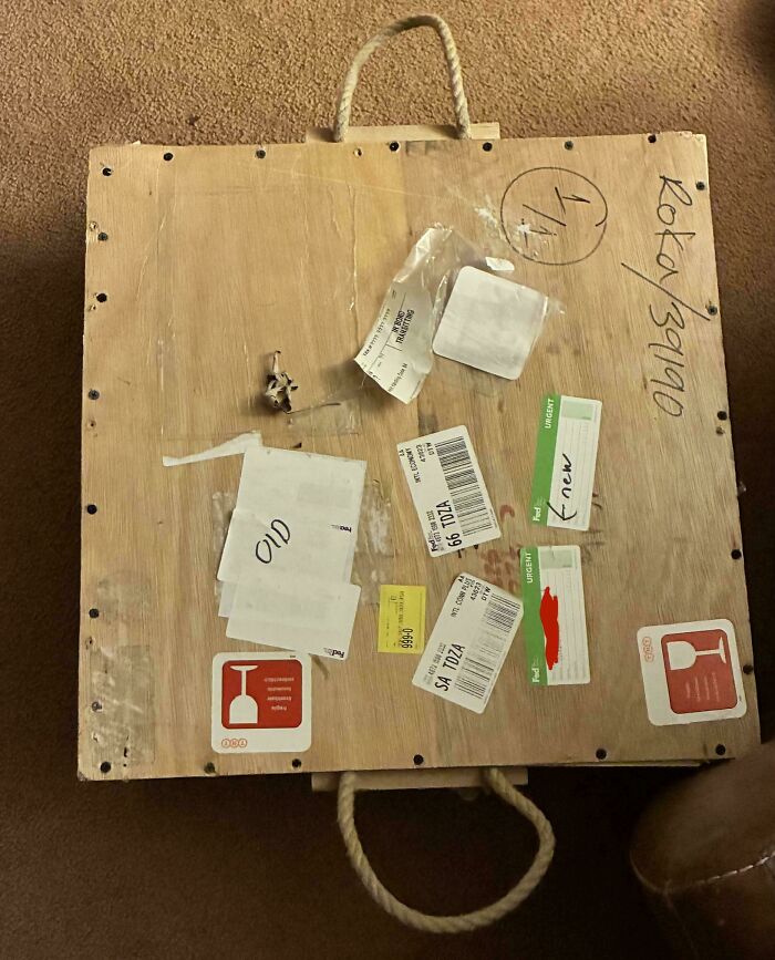 Wooden crate with multiple shipping labels and rope handle