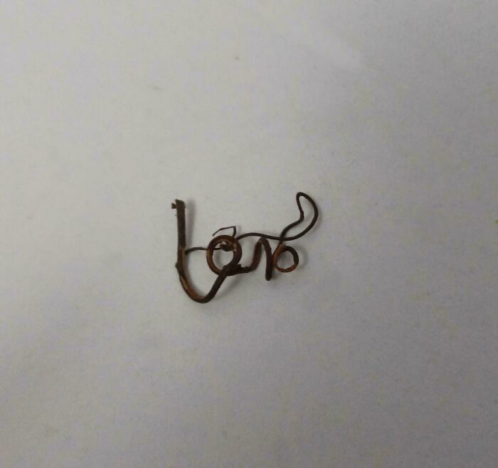 Rusty wire bent into word love on plain light background
