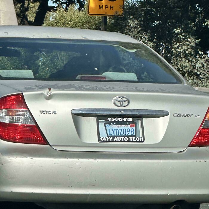 Damaged Toyota Camry with dented trunk and scratch marks under license plate
