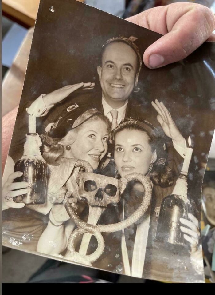 Old black and white photo of people posing with a skull art piece