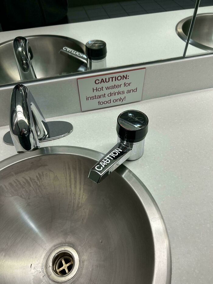 Hot water faucet with caution sign for instant drinks in school bathroom sink