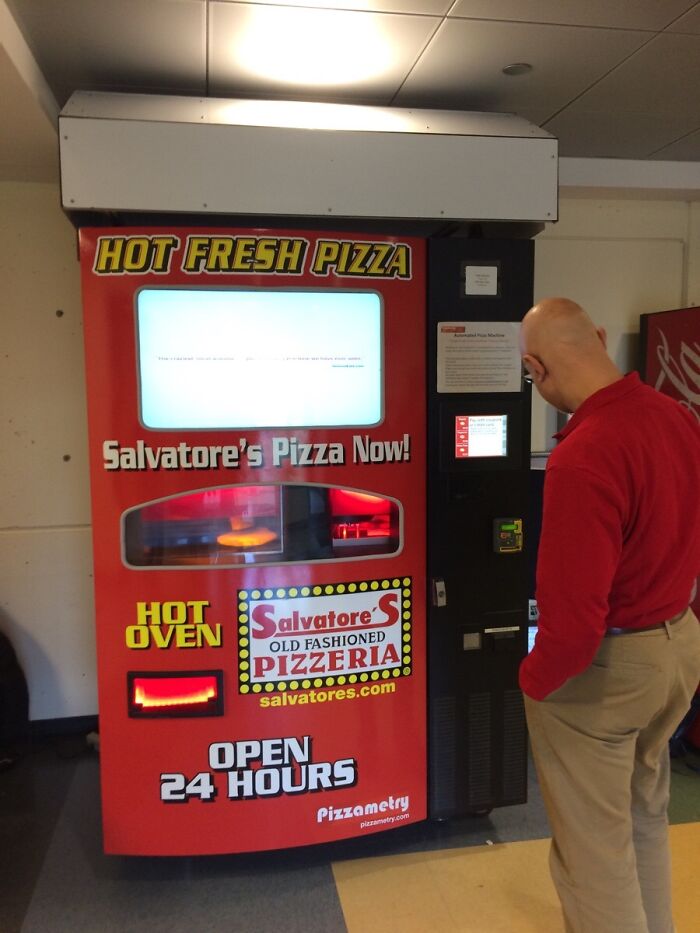 Red pizza vending machine offering hot fresh pizza 24 hours in a university setting