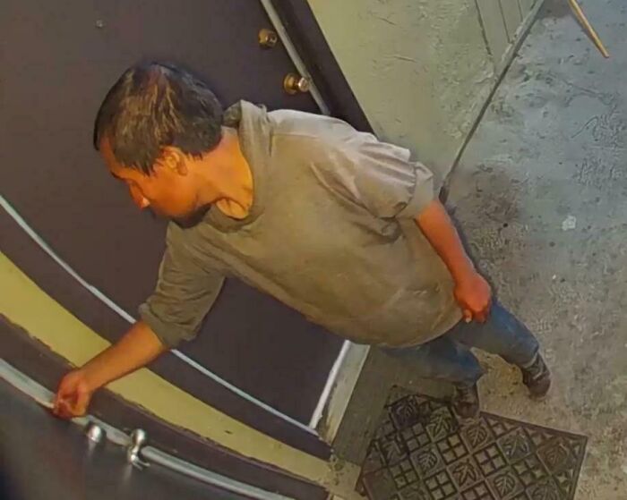 Man reaching to open door captured by security camera