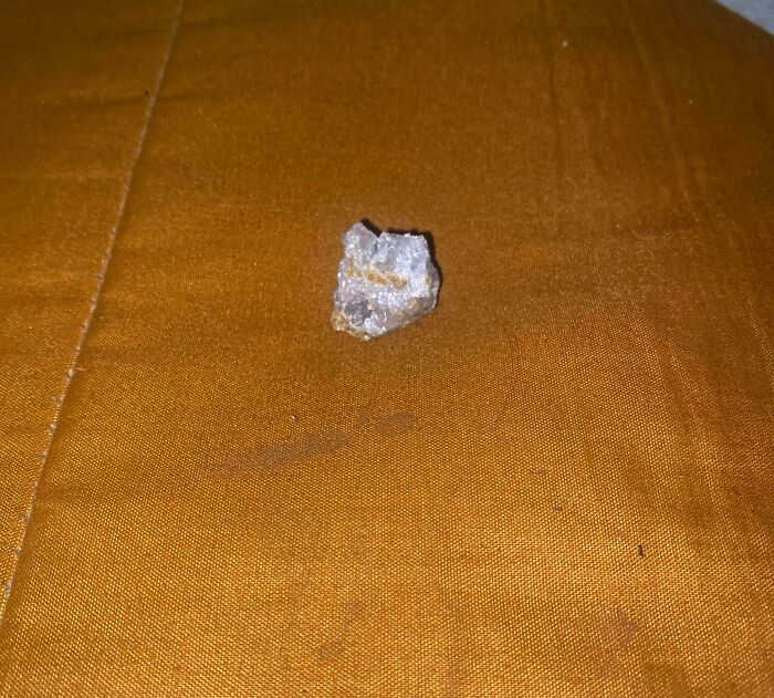 Small crystal rock resting on textured golden brown fabric