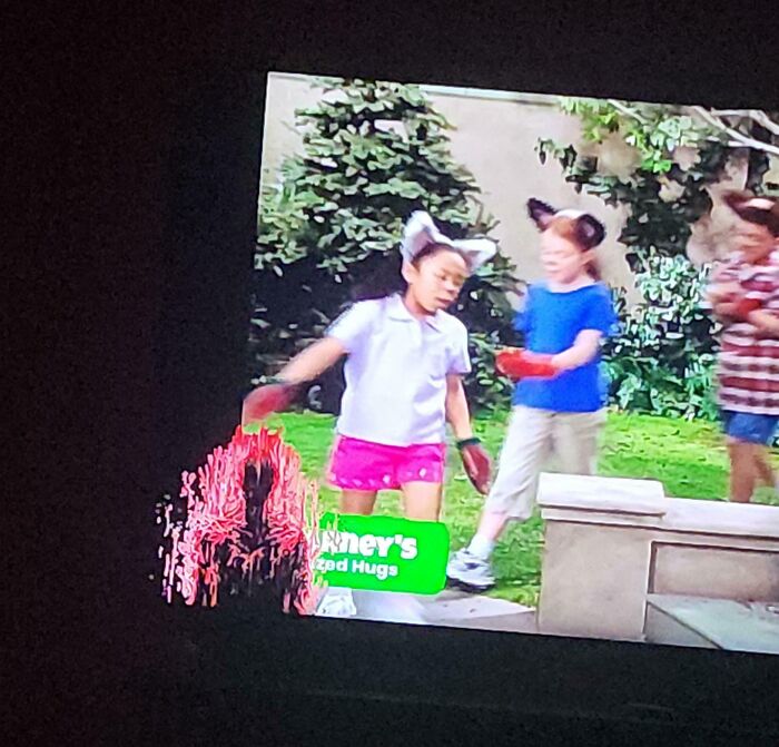 Blurry TV screen with children and distorted red digital artifact on the left side