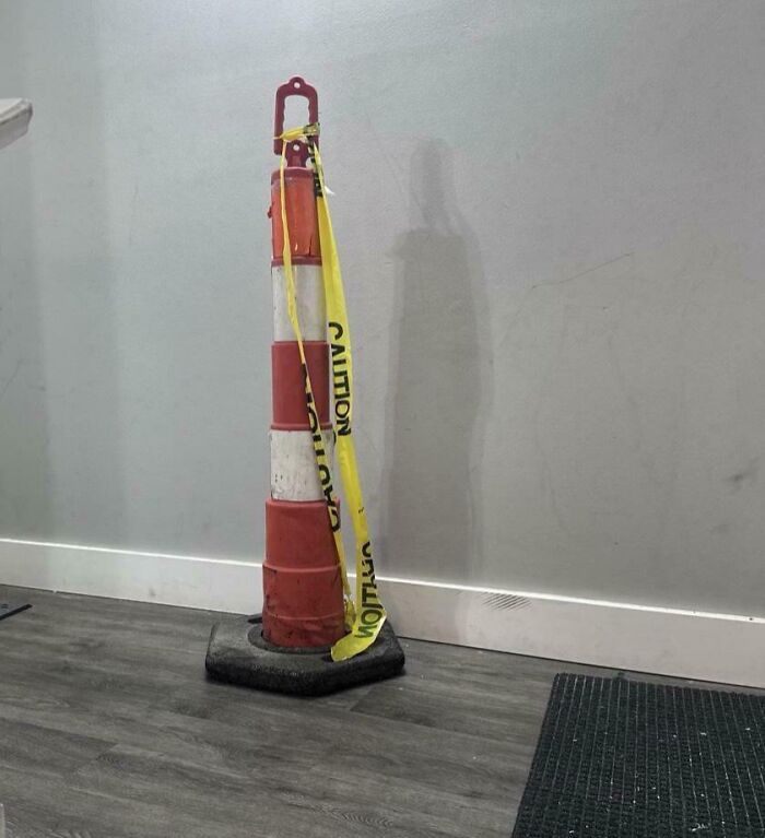 Stacked orange and white traffic cones with yellow caution tape indoors