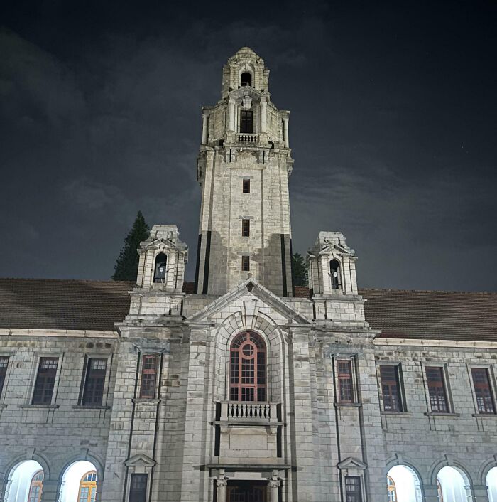 Historic school building at night with tall central tower and arched windows