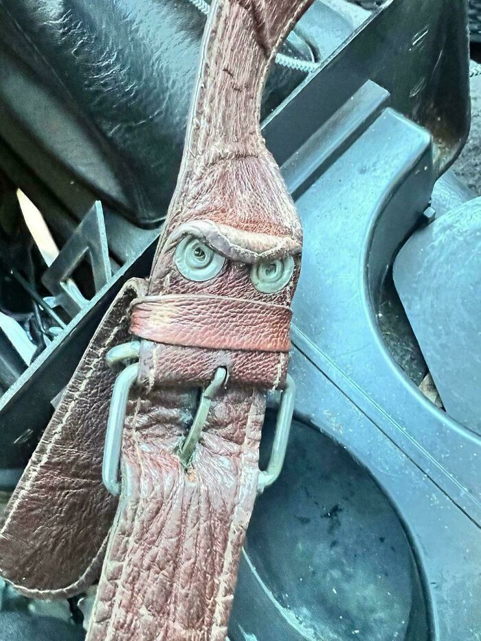 Worn leather belt buckle forming an angry face in pareidolia image