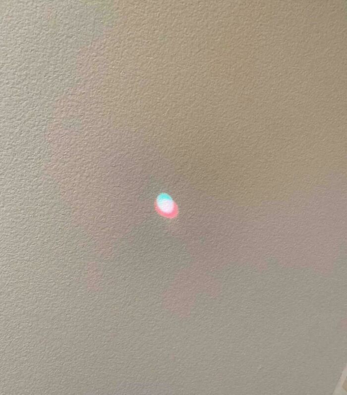 Blurred pastel light spot on wall resembling a face in pareidolia