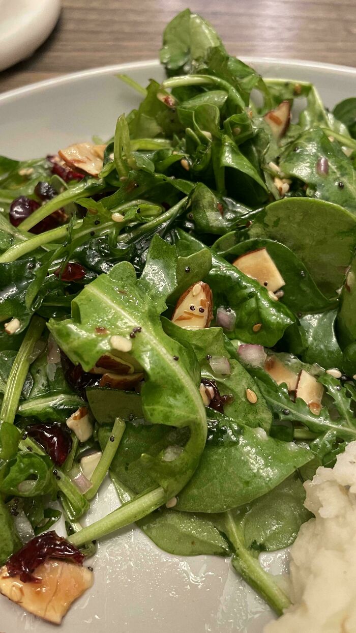 Close-up of salad with dressing showing a face-like pattern in pareidolia