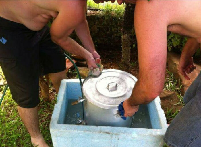 Two shirtless men washing a pot in a cooler creating pareidolia of people at work
