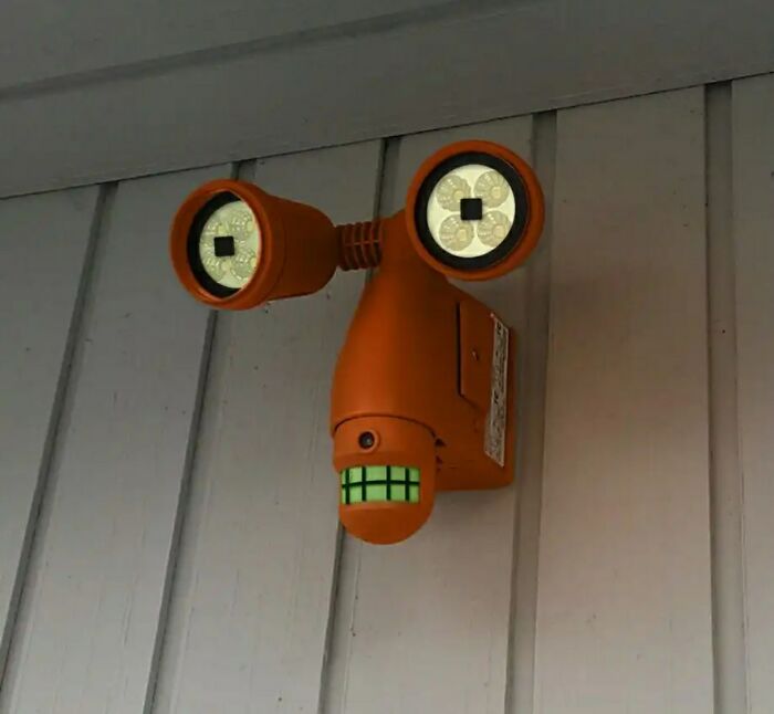 Wall light fixture resembling a face with big eyes and teeth pareidolia