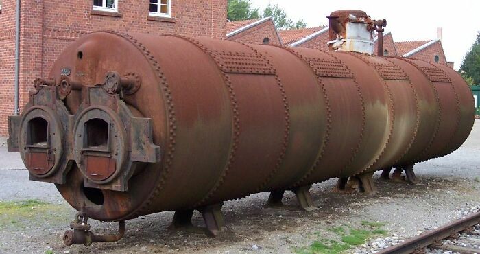 Rusty cylindrical machine with features resembling a surprised face pareidolia