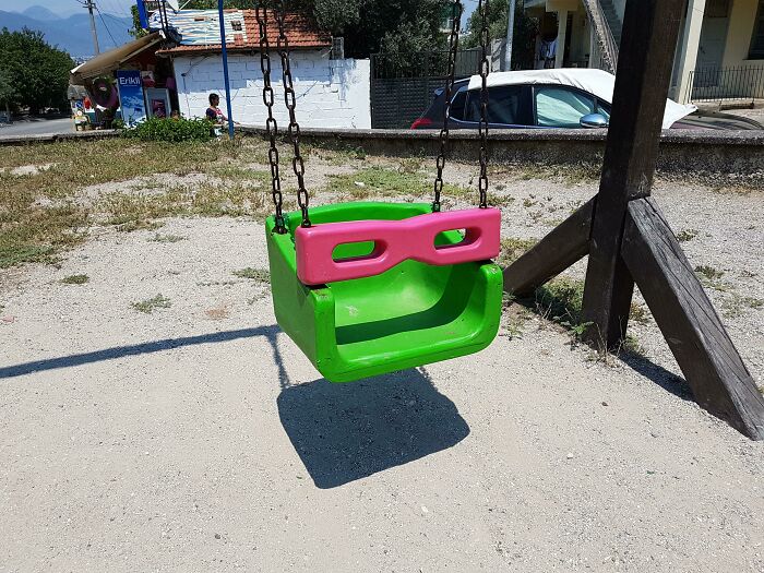 Child's swing with pink and green elements resembling a face with glasses pareidolia