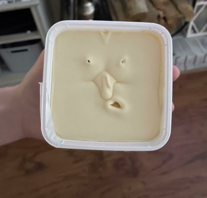 Block of cheese or butter with indents resembling a face with eyes and mouth
