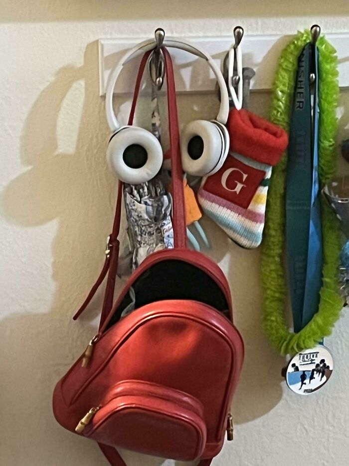 Hooks with items arranged to look like a face with headphones and a bag
