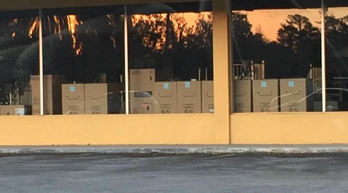 Reflection on window shows cartons and a sunset creating face-like pareidolia
