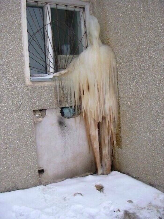 Pareidolia ice formation resembling a humanoid figure by a window on a snowy day
