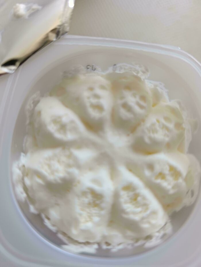 Pareidolia faces appearing in soft white cream inside a container