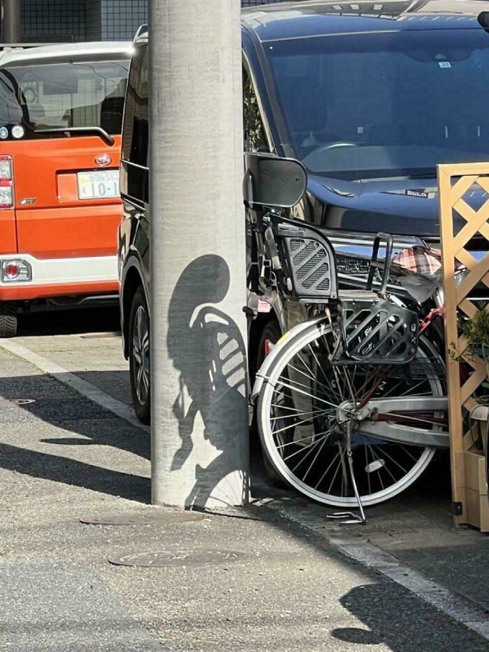 Bicycle shadow on pole creating skeletal figure illusion