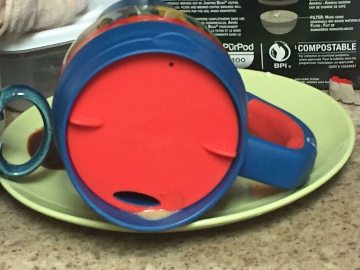 Lid of blue and red mug with spilled liquid looks like a surprised face