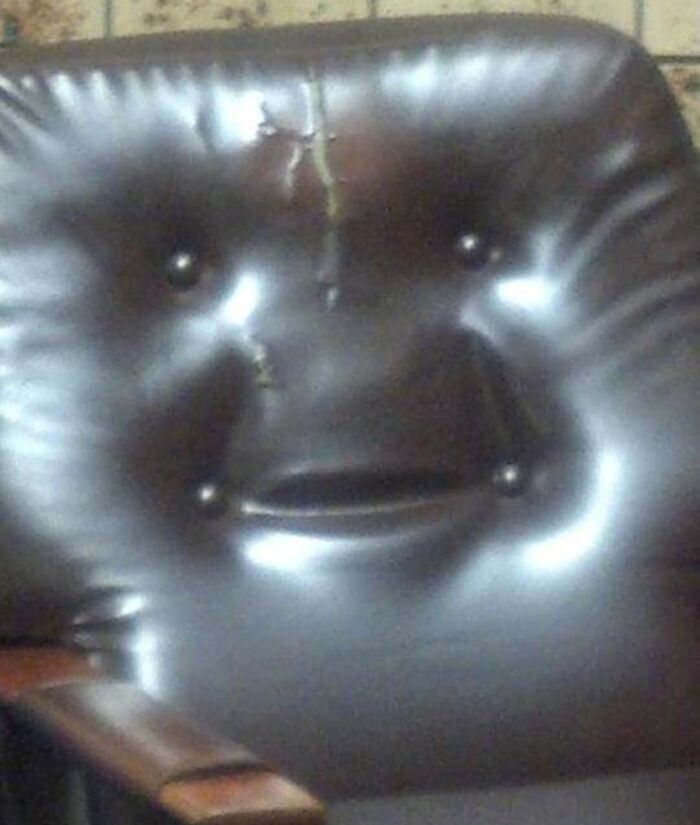 Cracked leather chair back with button indentations resembling a face