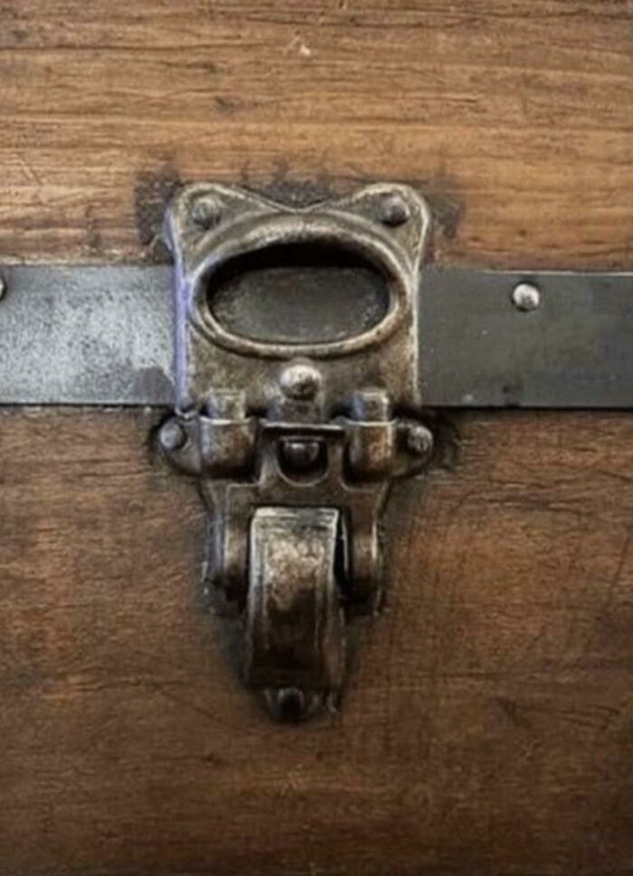 Metal latch on wood resembling a shocked face with open mouth