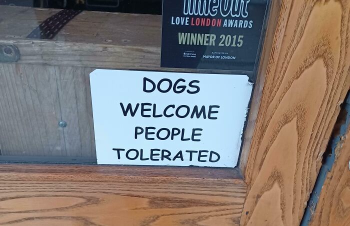 Humorous British sign saying dogs welcome people tolerated