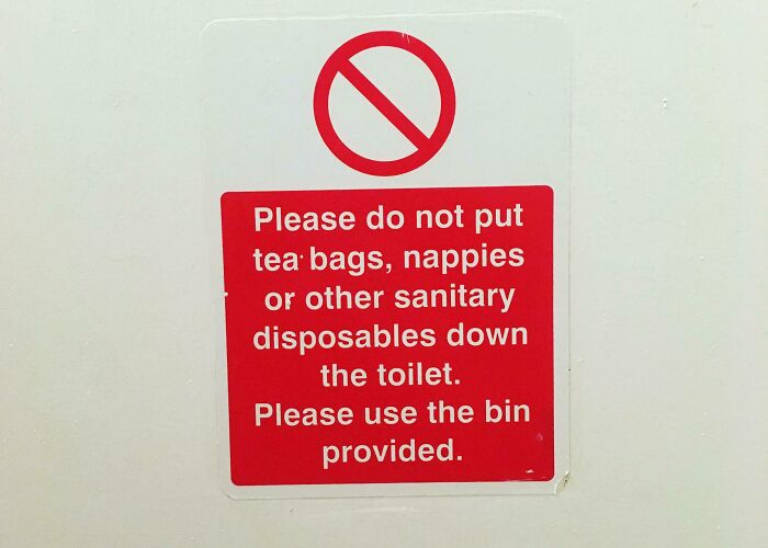 Red sign asking not to put tea bags or nappies in toilet