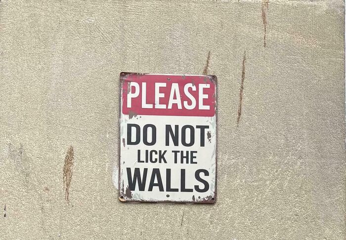 Weathered sign asking people not to lick the walls