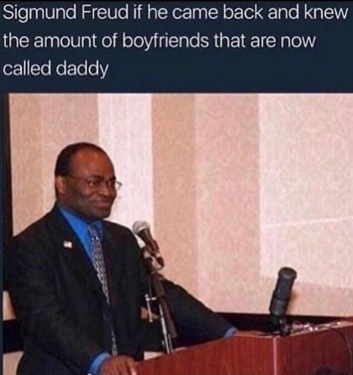 A smiling man at a podium with a microphone, representing a funny history meme about Sigmund Freud's reaction to modern slang.