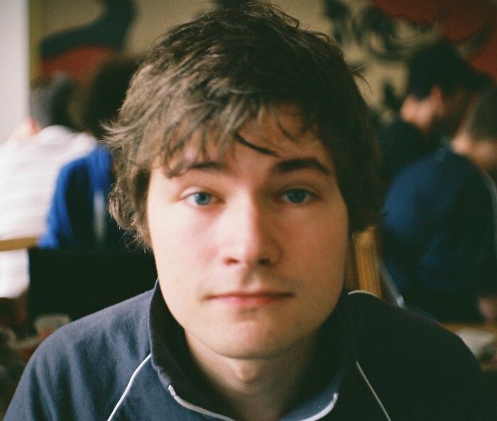 Daniel Rosenfeld with blue eyes and brown hair, wearing a dark blue zip-up shirt, looking directly at the camera.