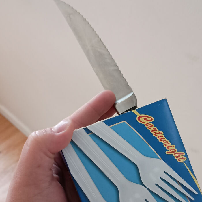Knife cutting into plastic fork packaging creating multi-tool